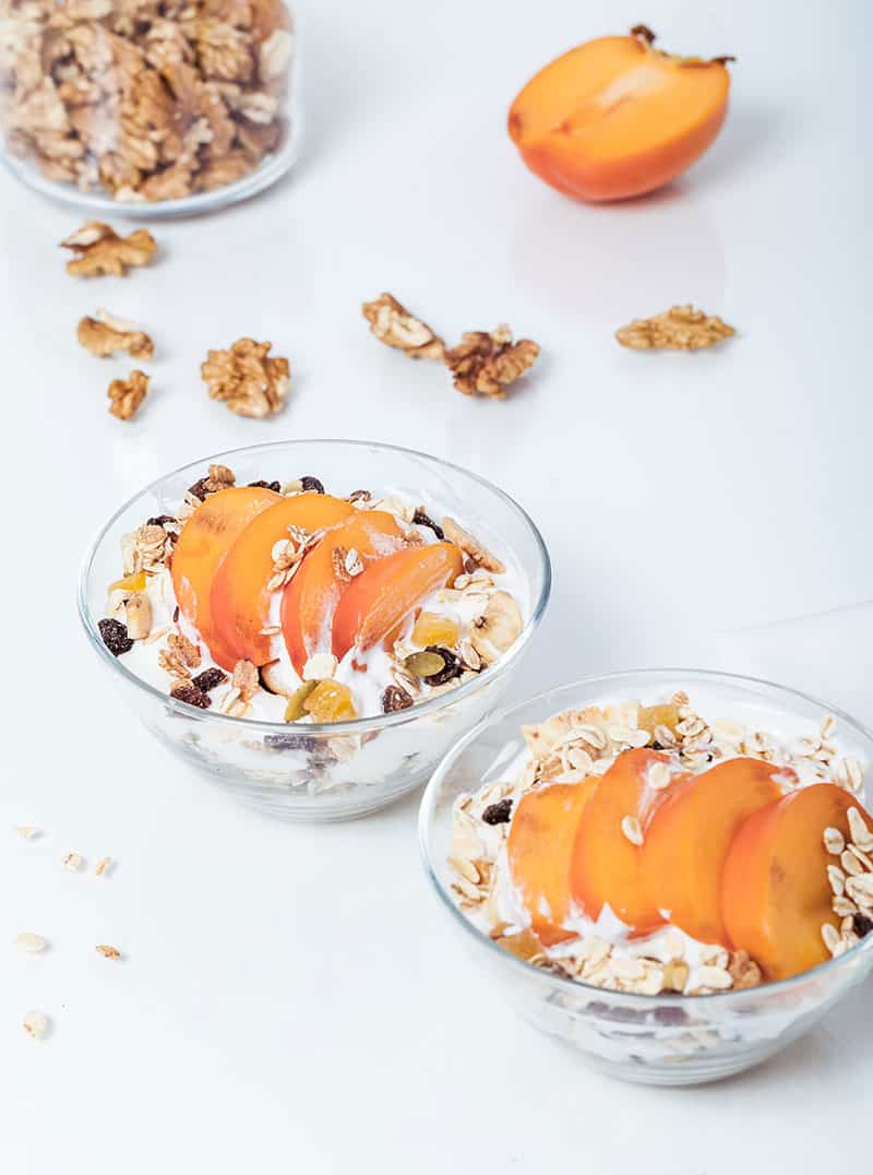 Yoghurt bowls with granola and sliced persimmon