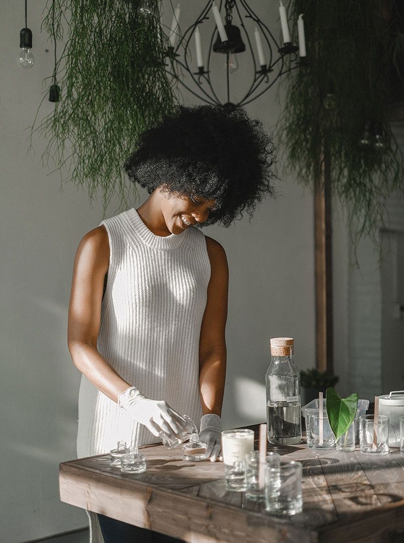 Woman arranging glass jars and candles indoors