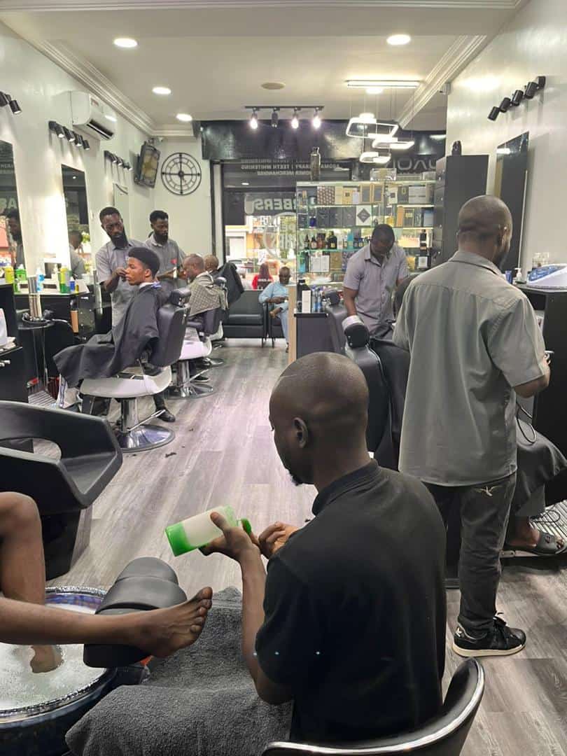 Busy barbershop with clients receiving haircuts and pedicure