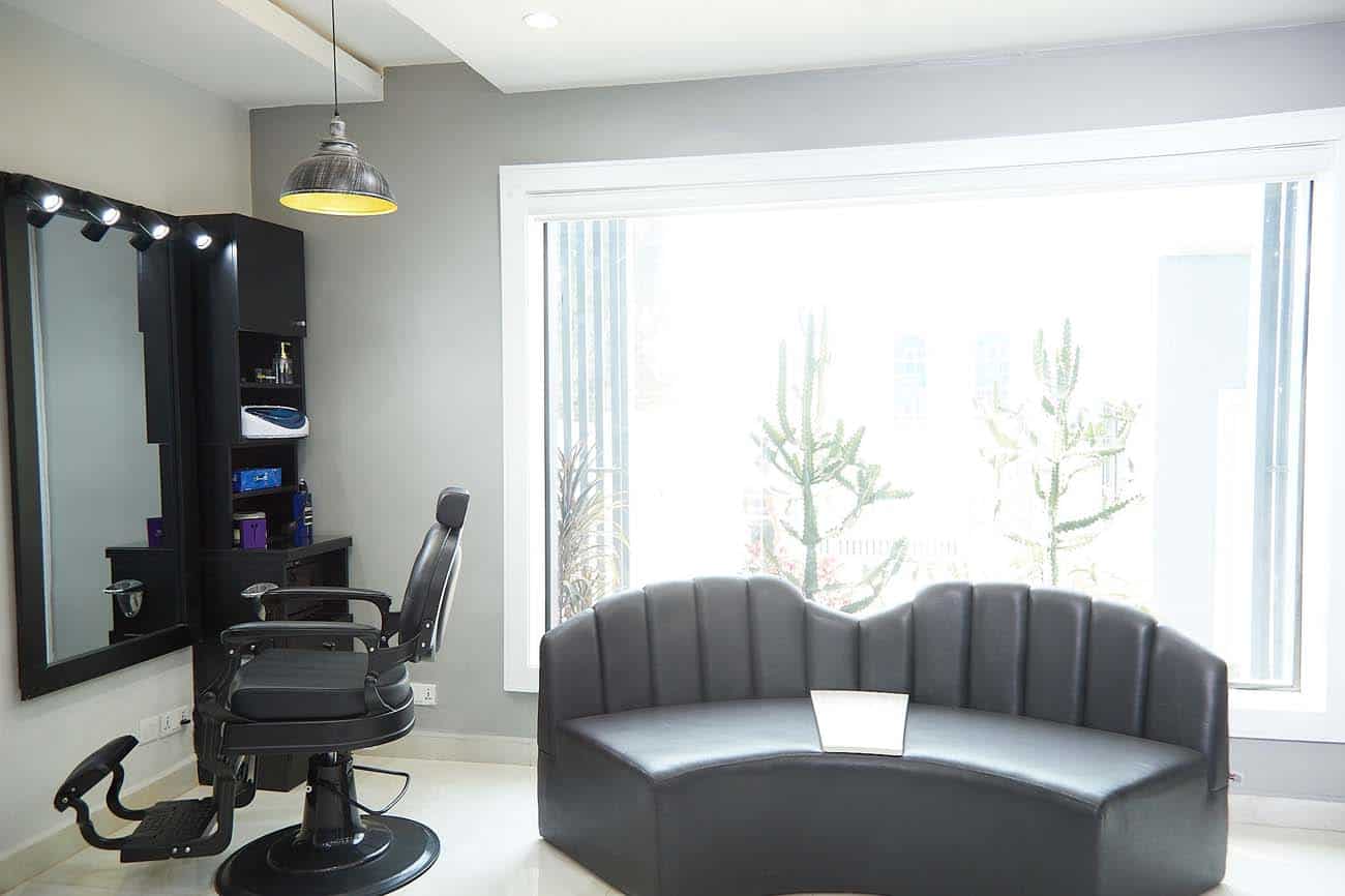 Modern hair salon interior with styling chair and sofa