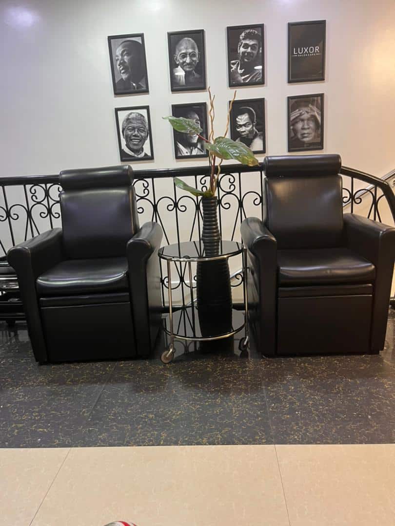 Two black leather armchairs with portraits behind
