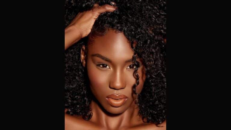 Close-up portrait of woman with curly hair, hand raised