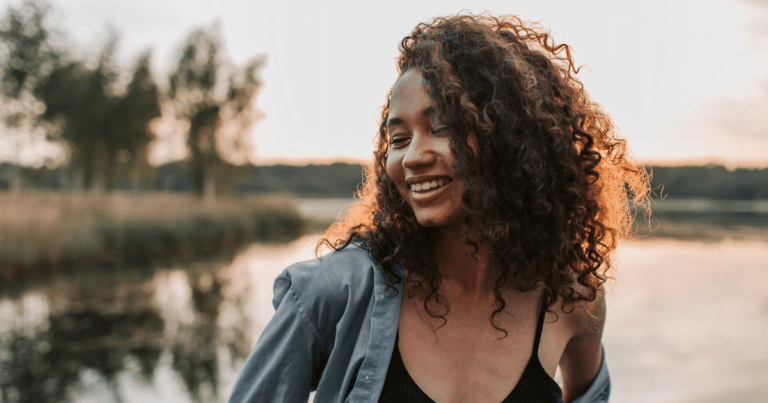 Smiling woman by lakeside at sunset