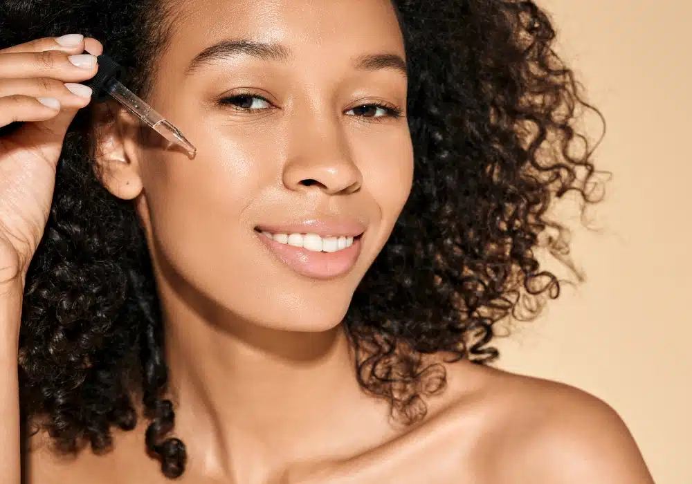 Woman applying facial serum with dropper to cheek
