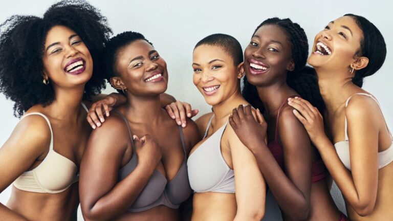 Five smiling women in bras posing together
