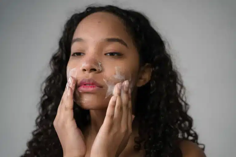 Woman applying facial cleanser to her face