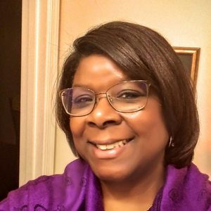 Smiling woman wearing glasses and purple top indoors