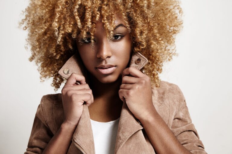 Woman with curly blonde hair holding suede jacket collar