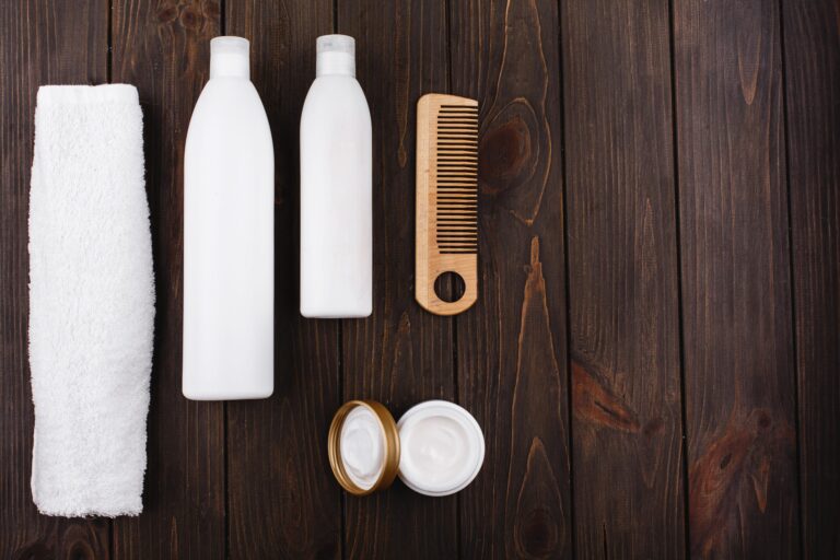 Haircare products, towel and wooden comb on table