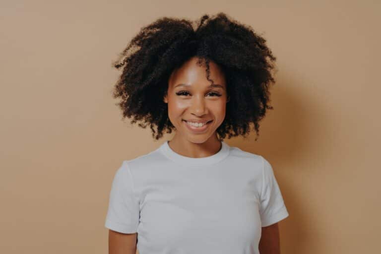 Smiling woman with curly hair on beige background