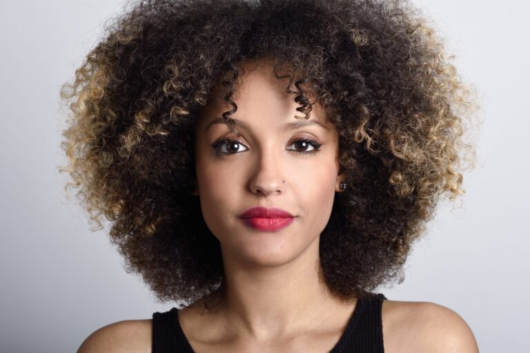 Close-up portrait of woman with curly hair and red lipstick