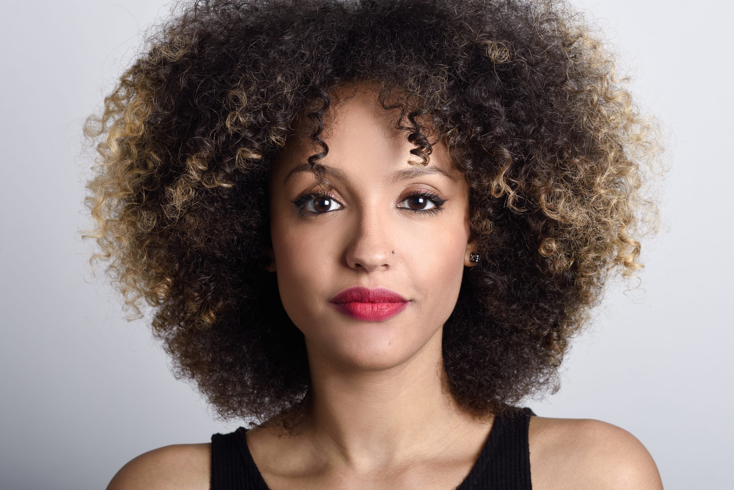 Close-up portrait of woman with curly hair and red lipstick