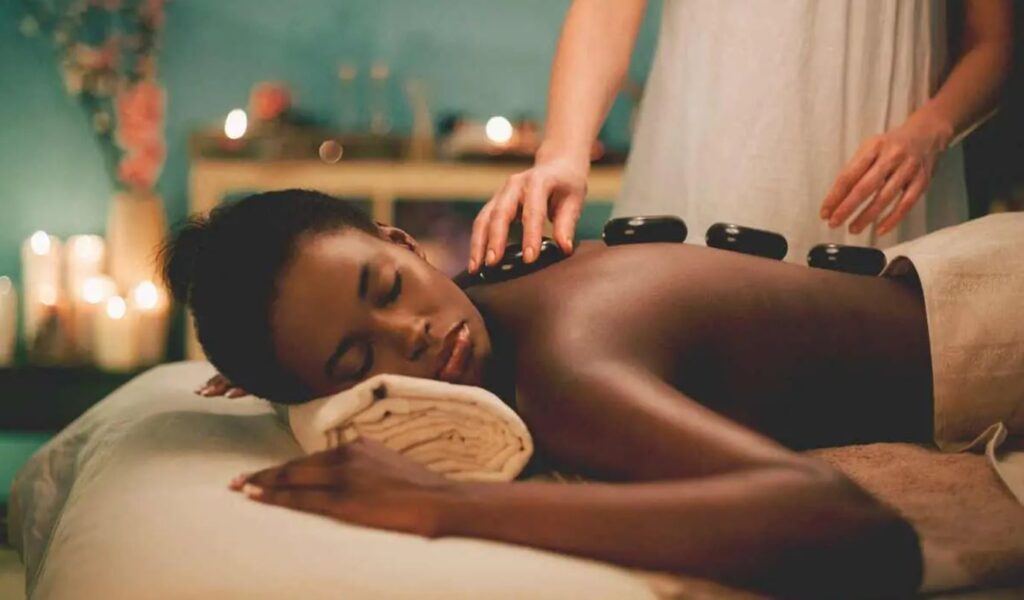 Woman receiving hot stone massage in candlelit spa