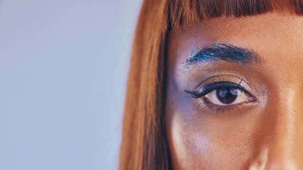 Close-up of woman's eye with blue glitter eyebrow