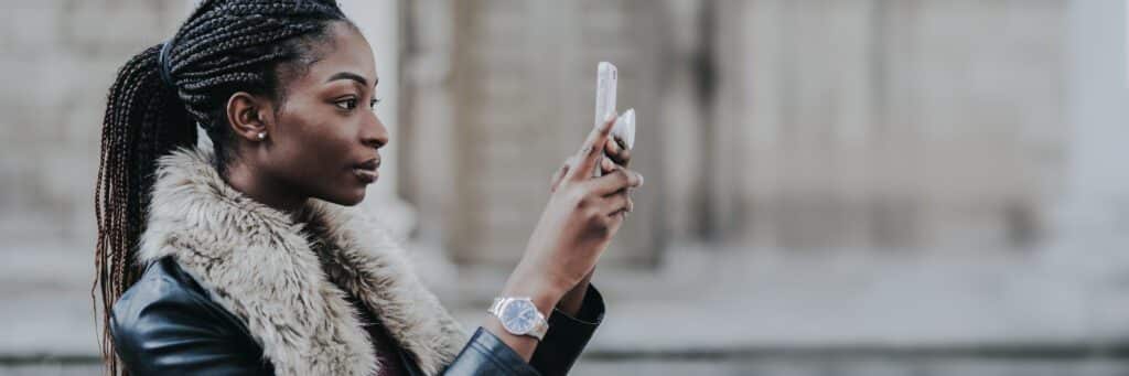 Woman with braided hair using smartphone outdoors