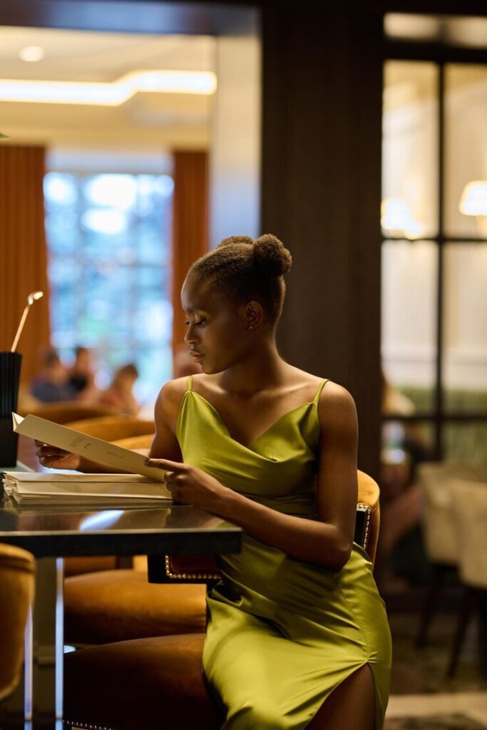 Woman in green dress reading menu in restaurant