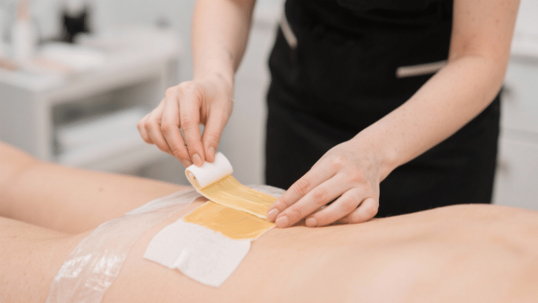 Beautician applying waxing strip to client's leg