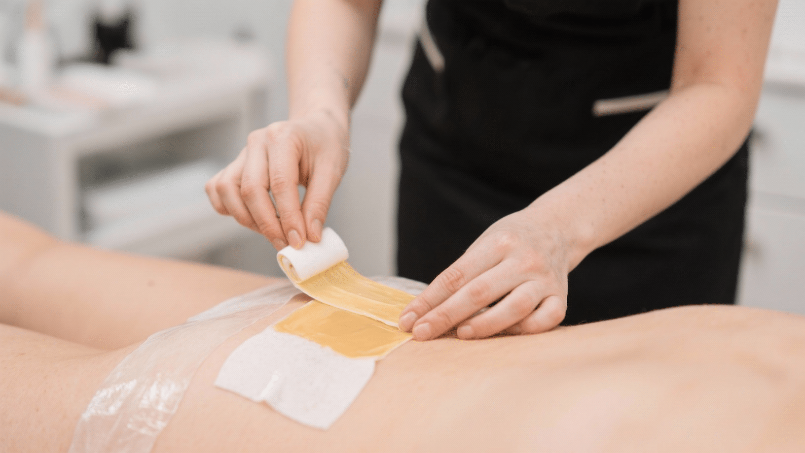 Beautician applying waxing strip to client's leg