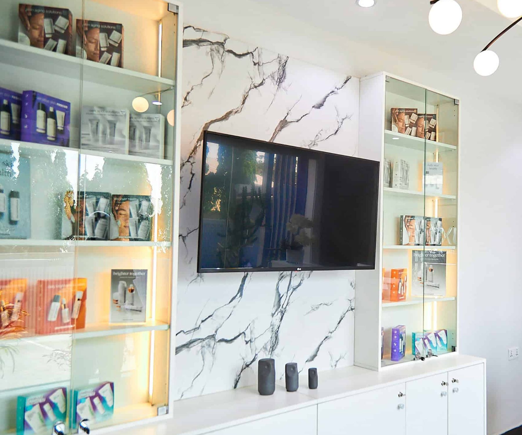 Wall-mounted television on marble wall with display cabinets